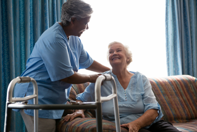 nurse helping senior women in standing at nursing home